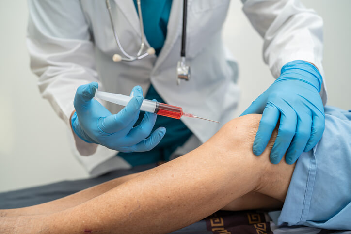 Traumatólogo en Madrid aplica una inyección de ácido hialurónico en la rodilla izquierda del paciente